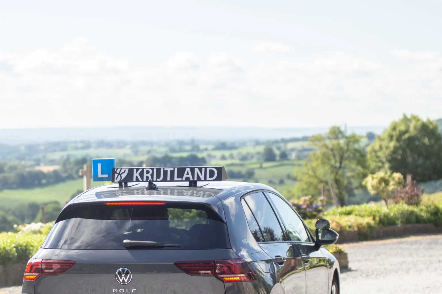 Driving school car with Krijtland roof sign in the hills of South Limburg