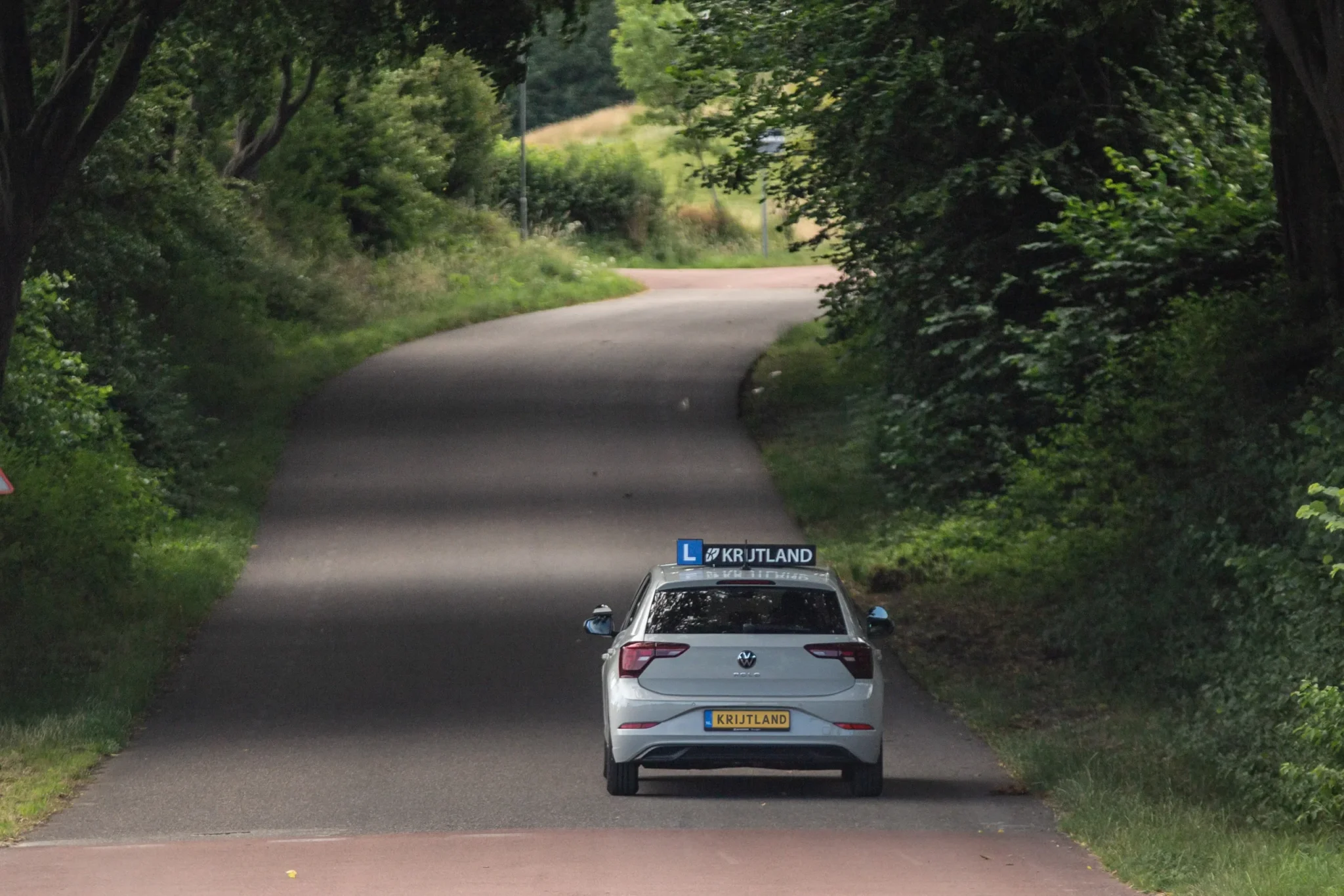 Lesauto met Krijtland-dakbord met uitzicht over het heuvelland